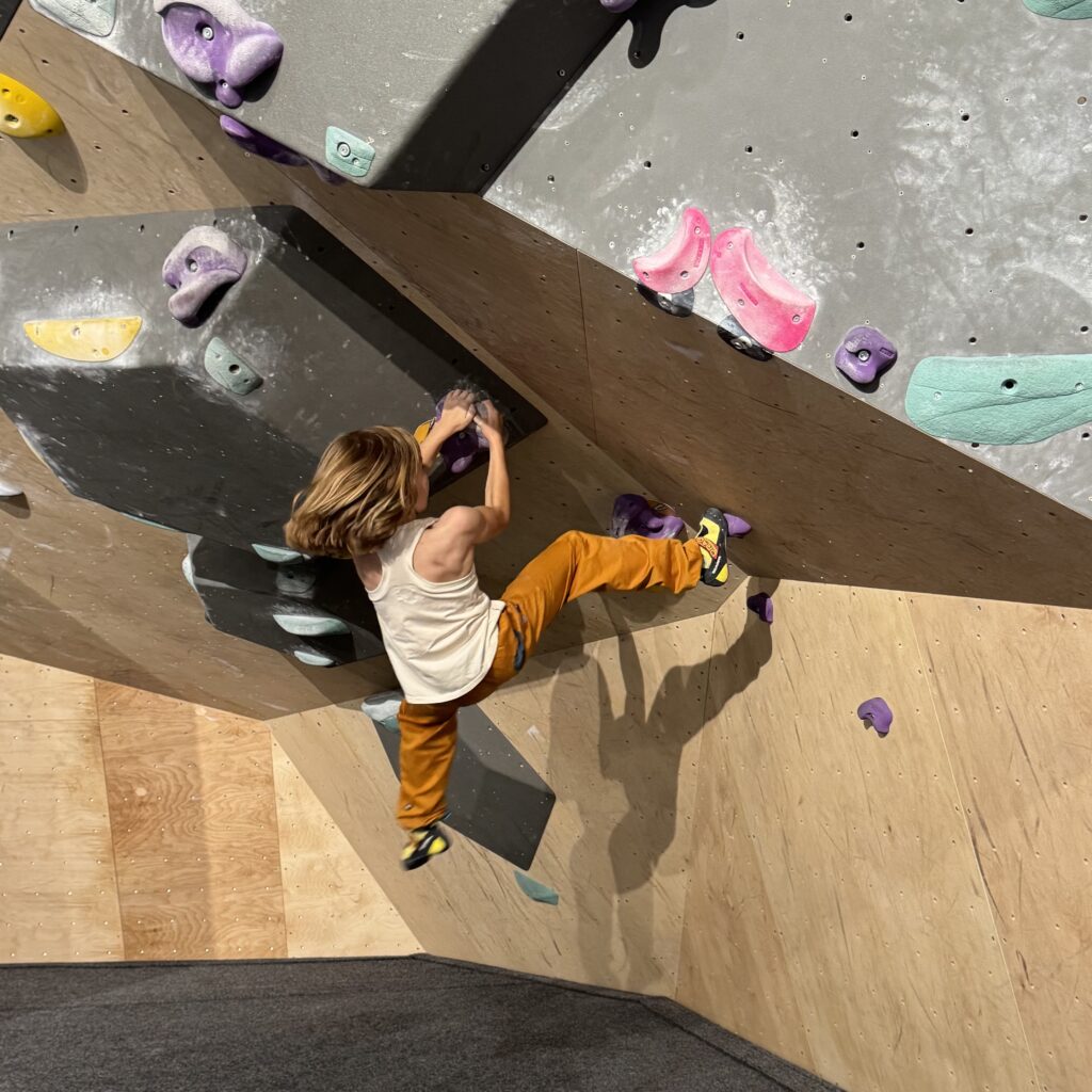 Kleines Kind bouldert am Überhang mit sehr kleinen Griffen